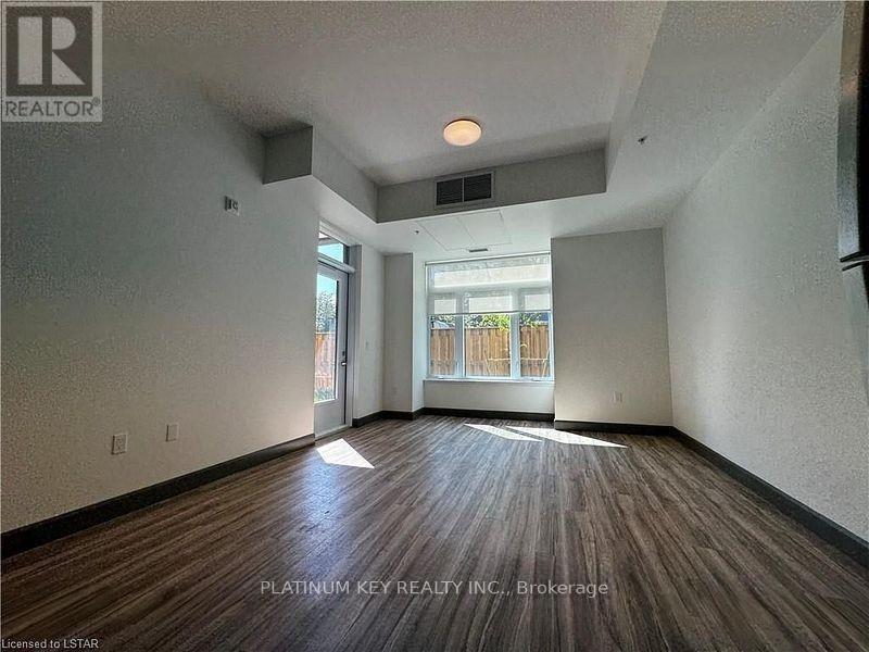 A room with wood flooring and a window overlooking a fence.