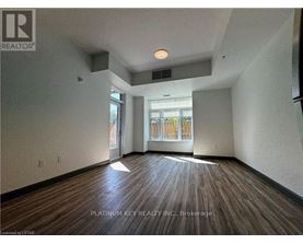 A room with wood flooring and a window overlooking a fence.