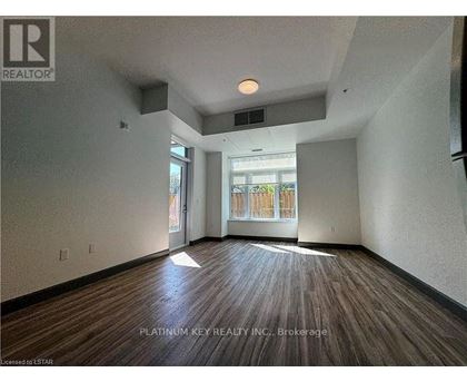 A room with wood flooring and a window overlooking a fence.