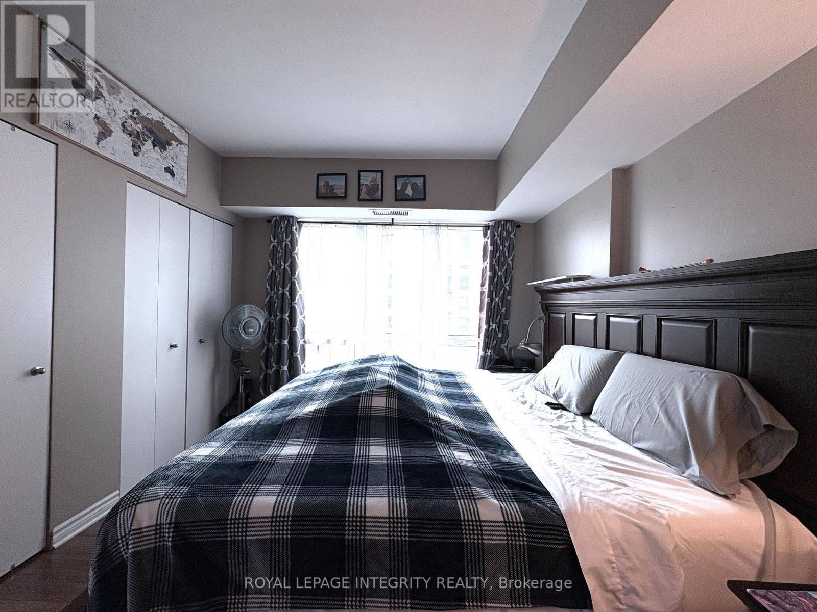 A bedroom with a bed covered in a plaid comforter.