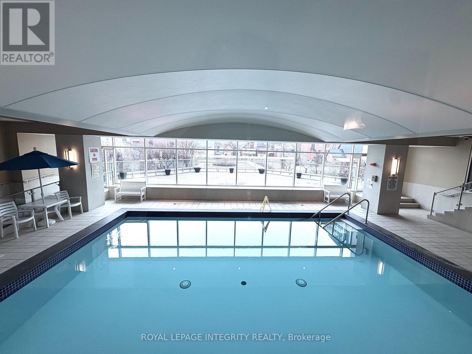 A swimming pool inside a building with a logo of Royal LePage Integrity Realty, Brokerage on the wall.