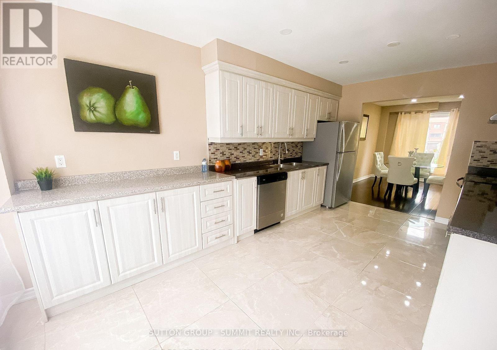 A kitchen with white cabinets and a marble countertop.