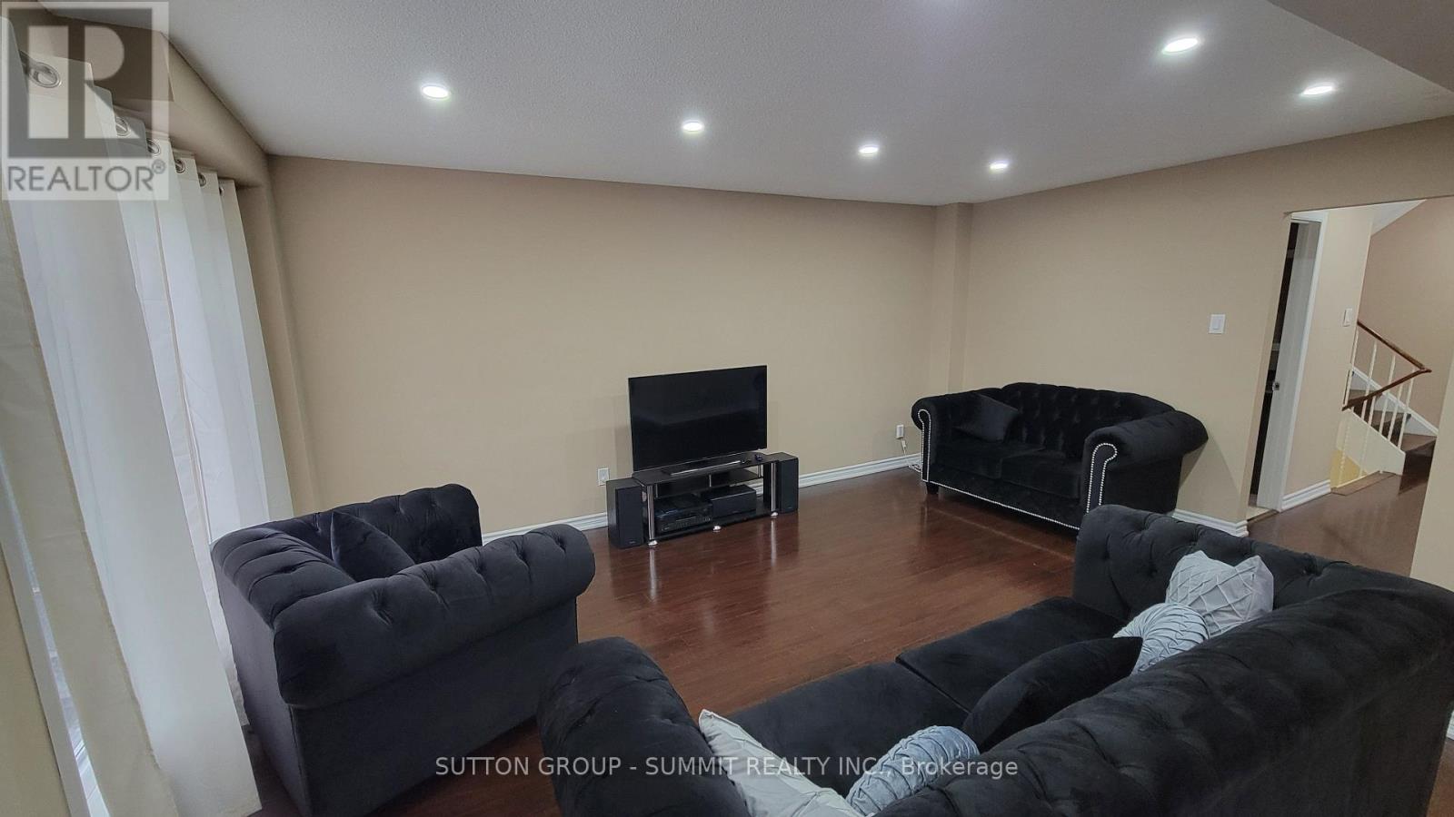 A living room with black furniture and a flat screen TV.