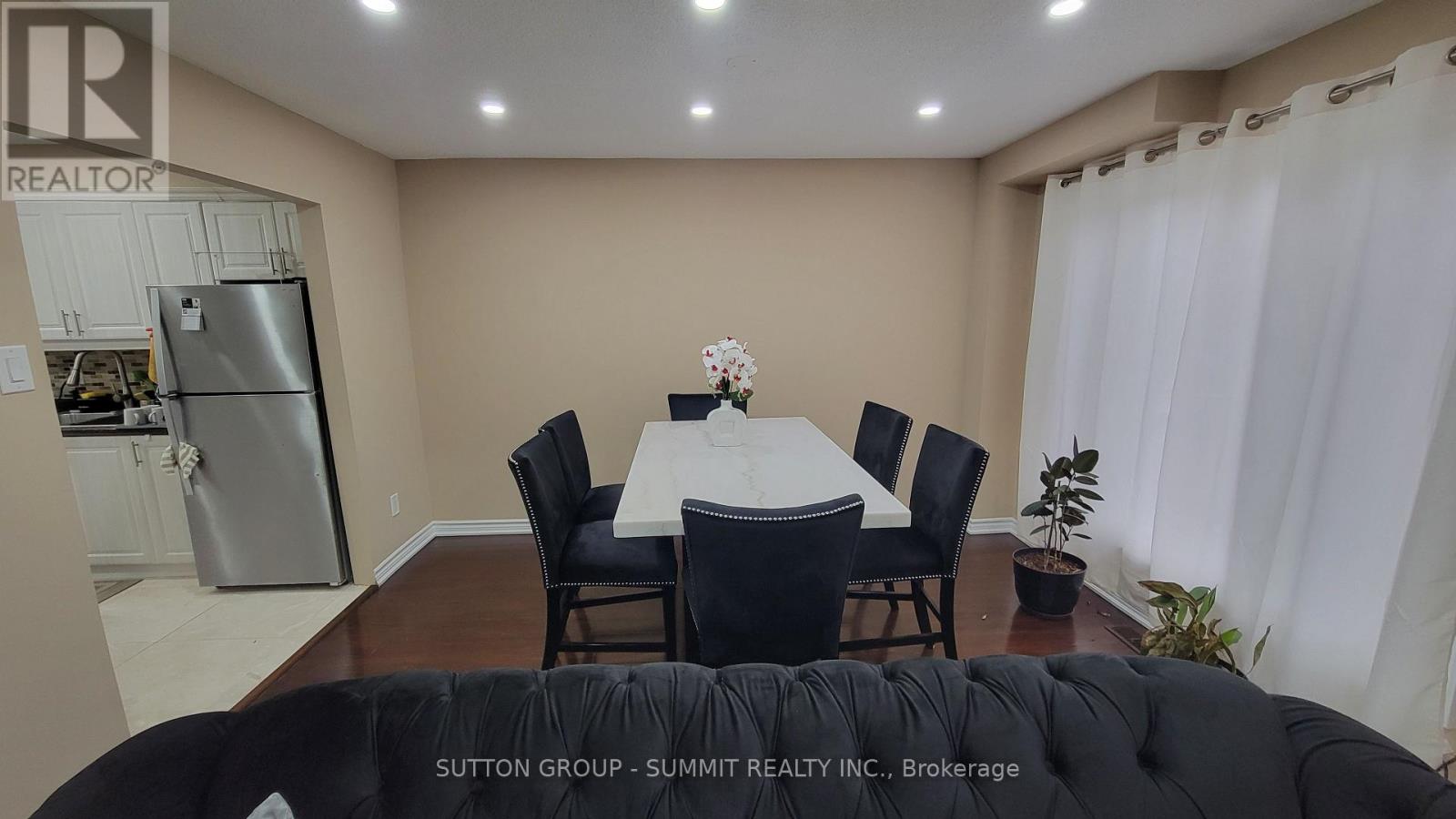 A dining room with a table set for four and a refrigerator in the background.