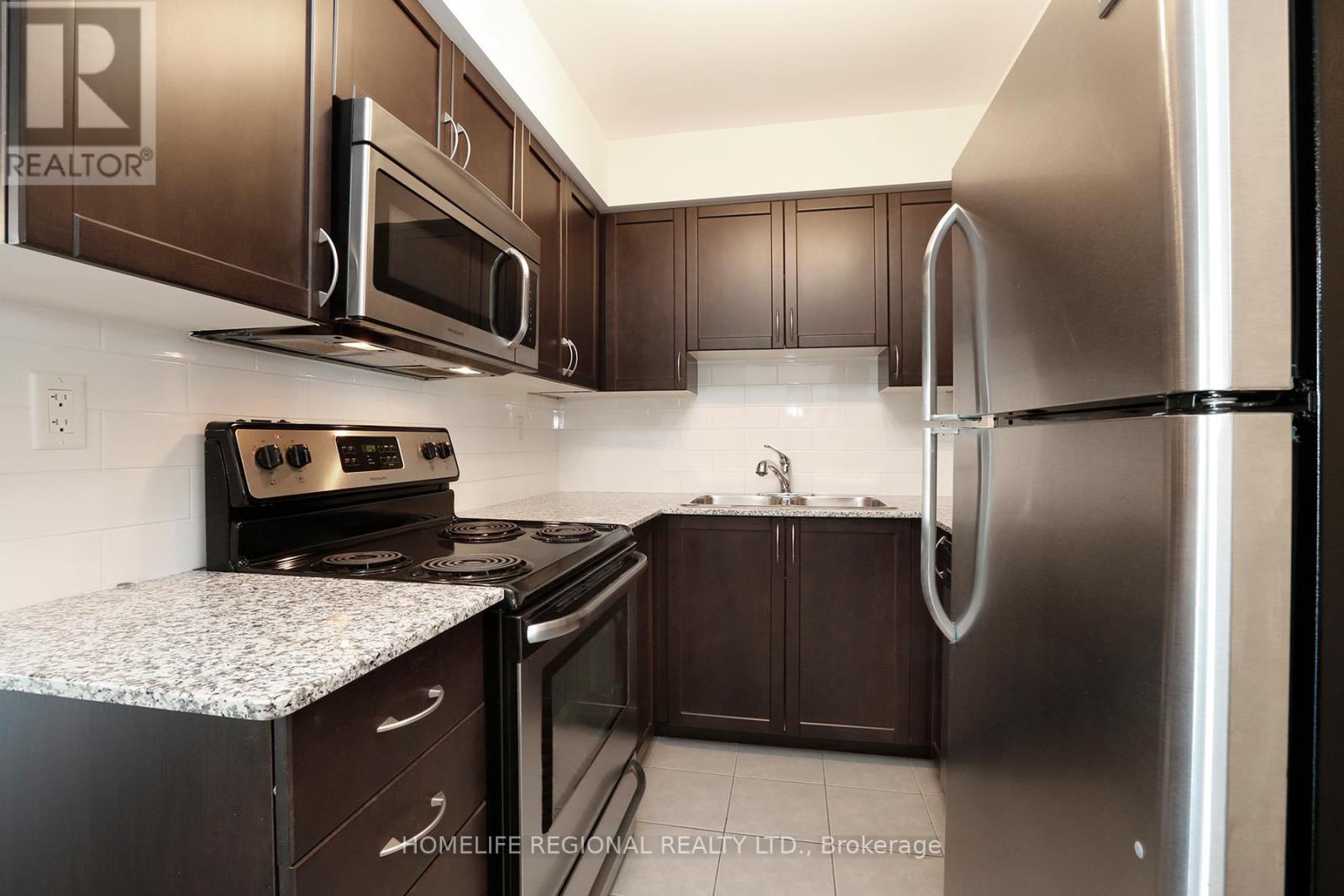 A kitchen with a refrigerator, oven, and microwave.