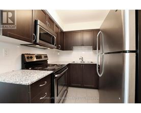A kitchen with a refrigerator, oven, and microwave.