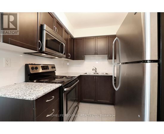 A kitchen with a refrigerator, oven, and microwave.