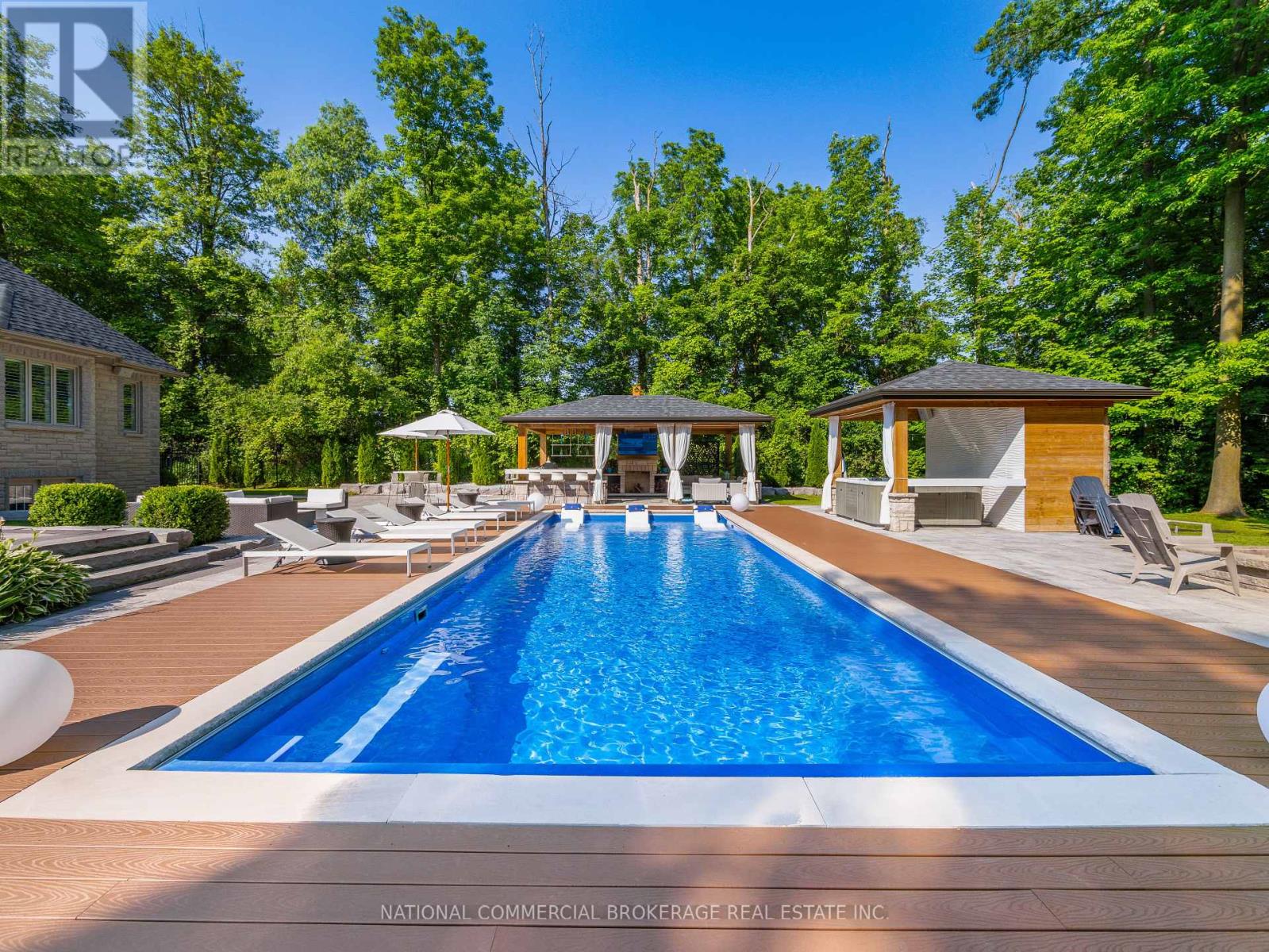 A pool surrounded by trees and a gazebo.