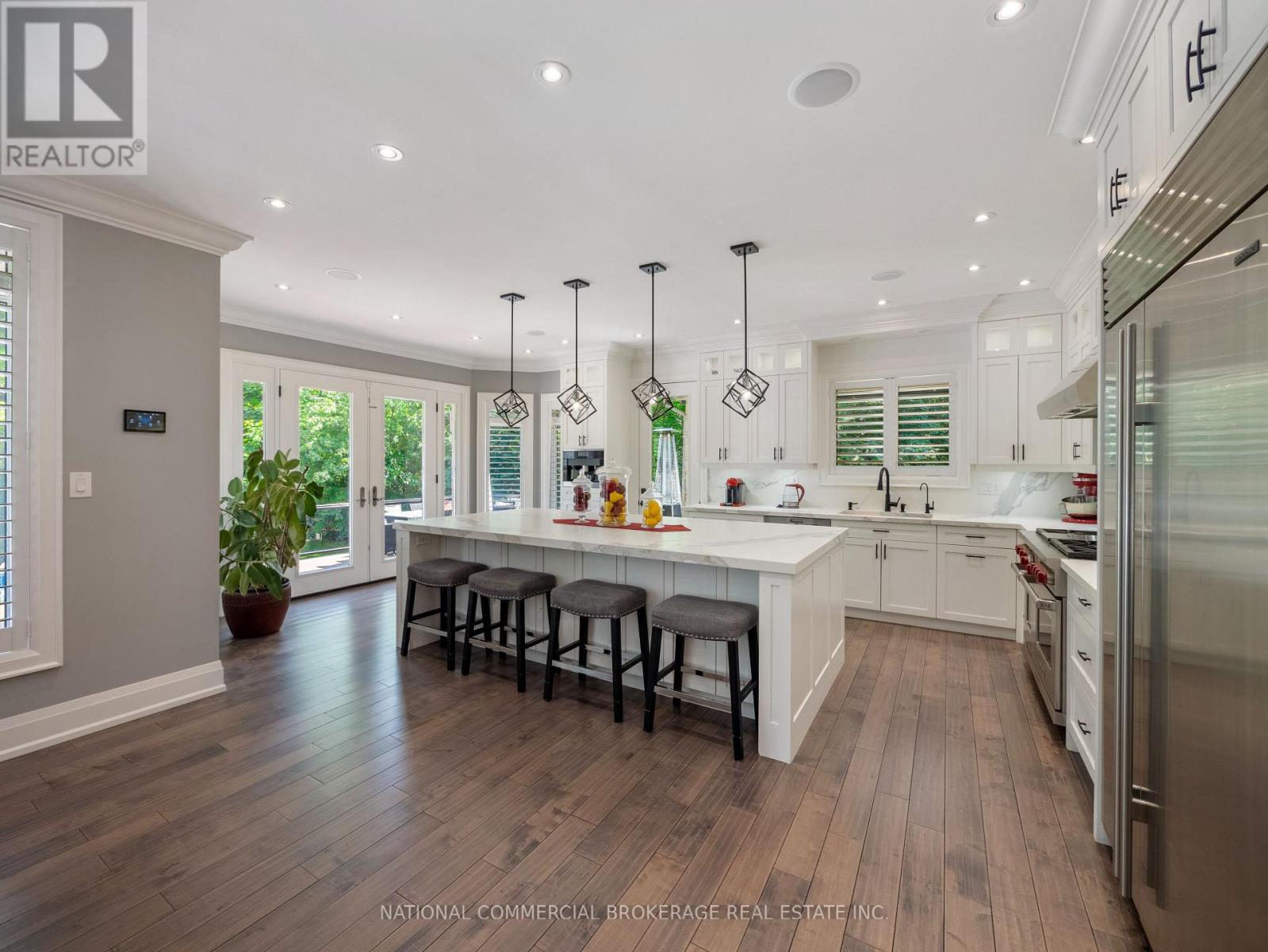 A modern kitchen with white cabinets and a wooden floor.