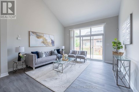 A living room with a grey couch and a glass table.