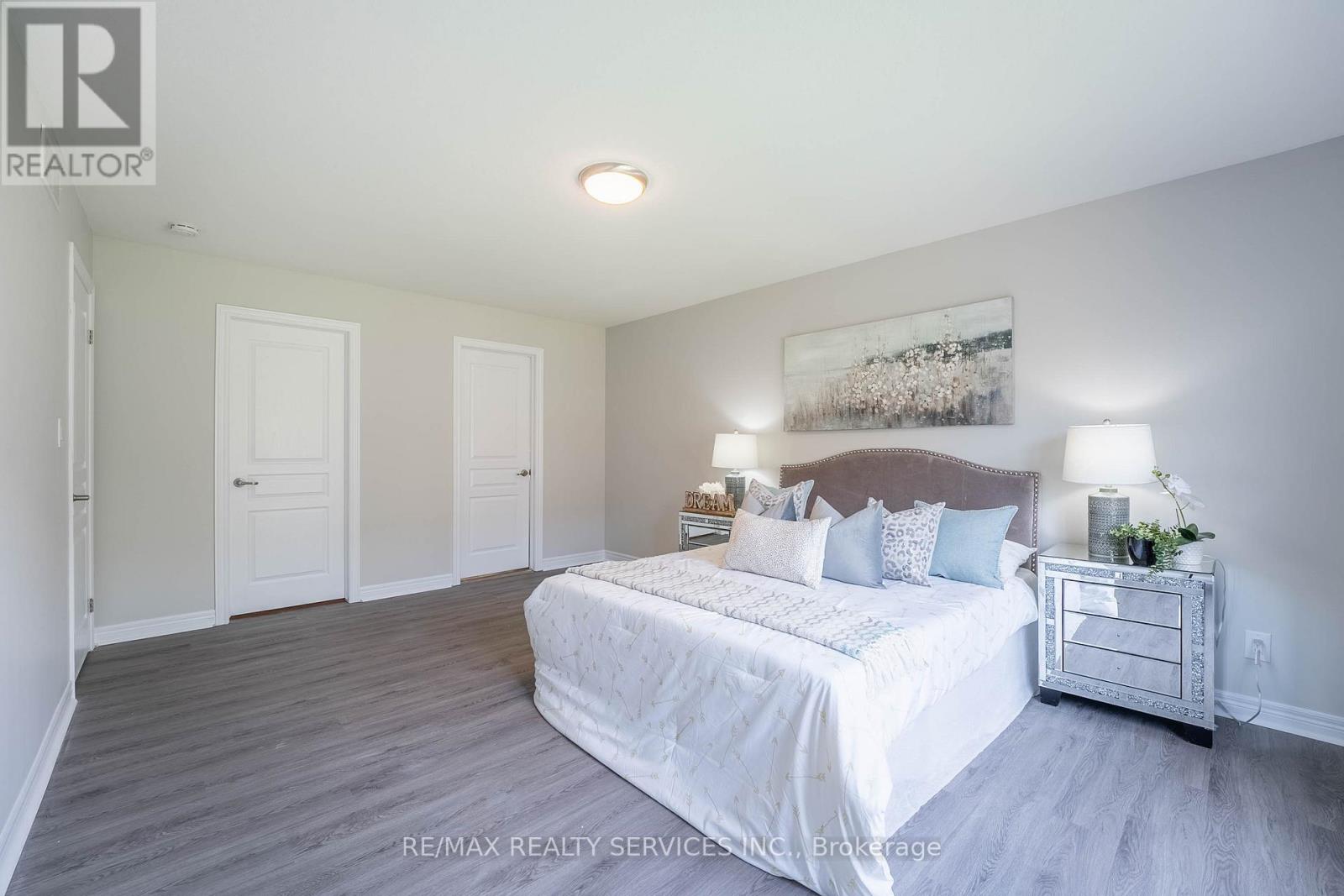 A bedroom with a large bed and a nightstand with a plant on it.
