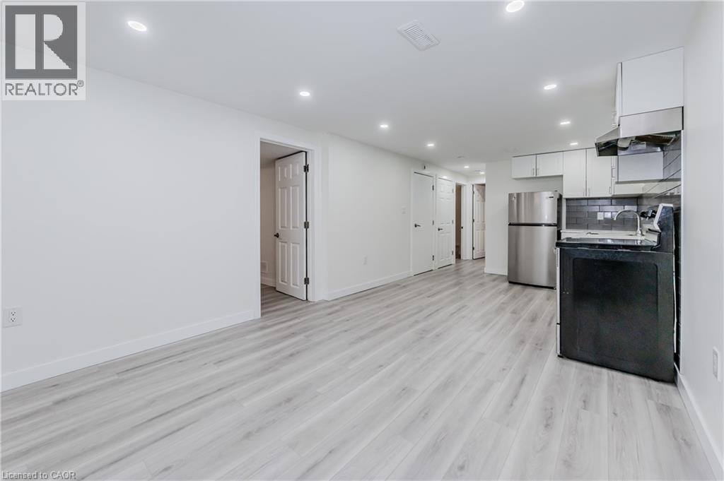 A spacious kitchen with a black fridge and wooden flooring.
