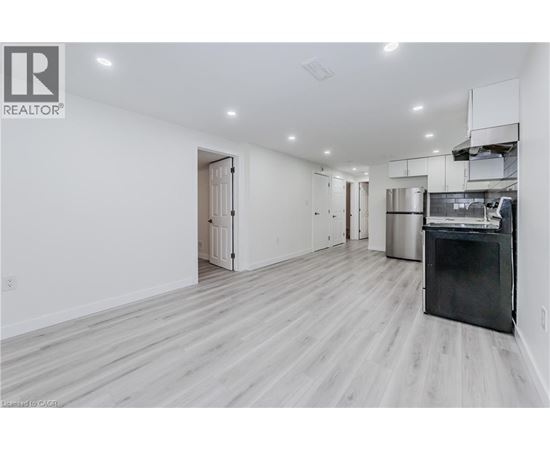 A spacious kitchen with a black fridge and wooden flooring.