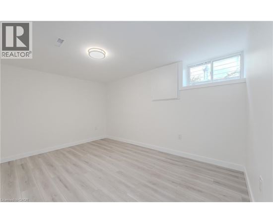 A spacious room with wooden flooring and a window.