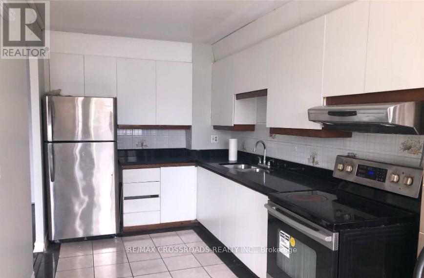 A kitchen with a stainless steel refrigerator and black countertops.