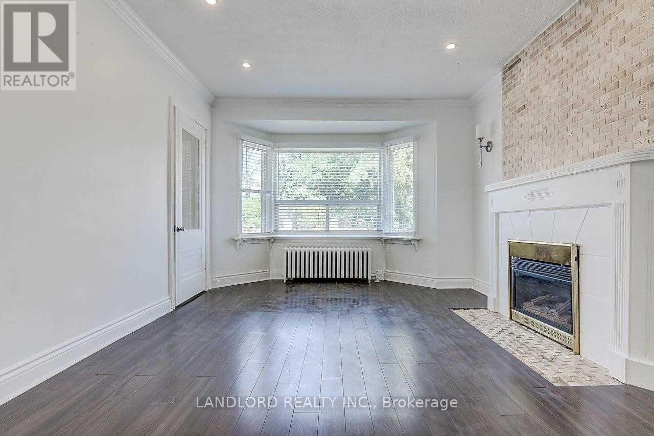 A spacious room with a fireplace and a window with blinds.