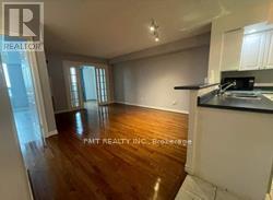 A room with wooden floors and white walls, with a window on the left side.