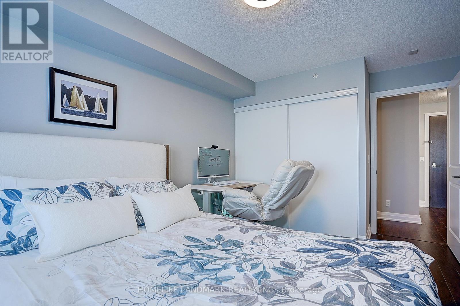A bedroom with a bed, a chair, and a painting on the wall.