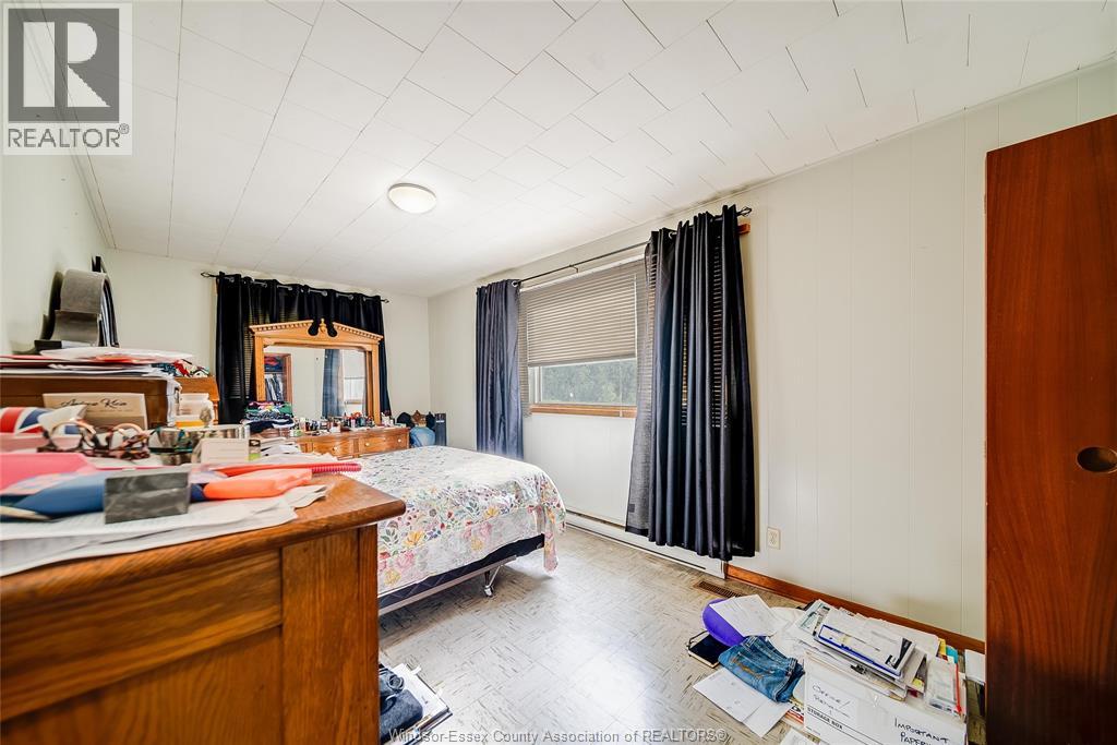 A bedroom with a bed, desk, and window with curtains.