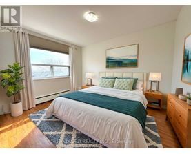 A bedroom with a large bed, a potted plant, and a painting on the wall.