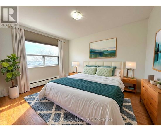 A bedroom with a large bed, a potted plant, and a painting on the wall.