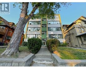 A tree stands in front of a building with a sign that says "LANDLORD REALTOR".