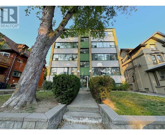 A tree stands in front of a building with a sign that says "LANDLORD REALTOR".