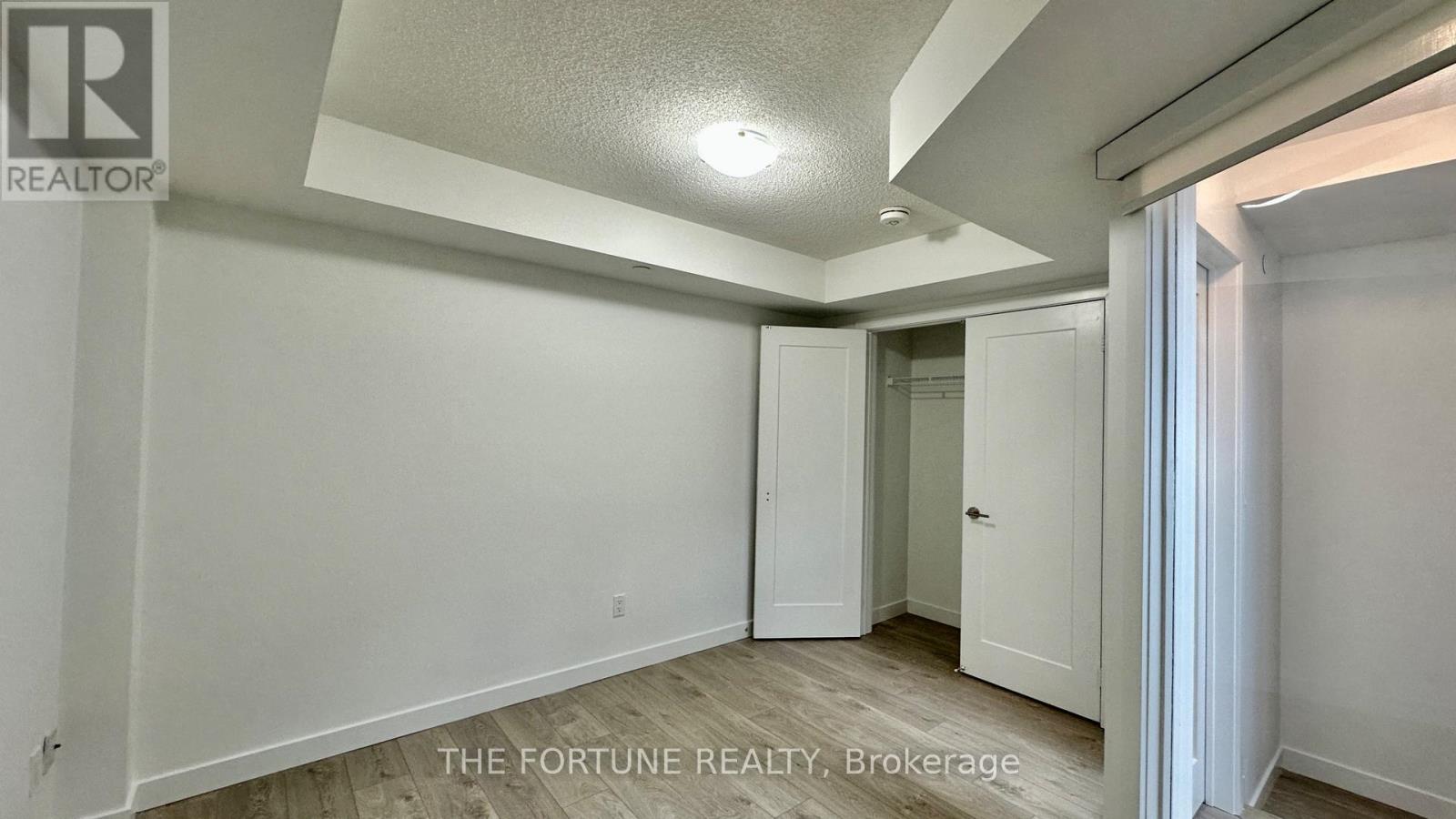 A realtor photo of a white bedroom with a door and a window.