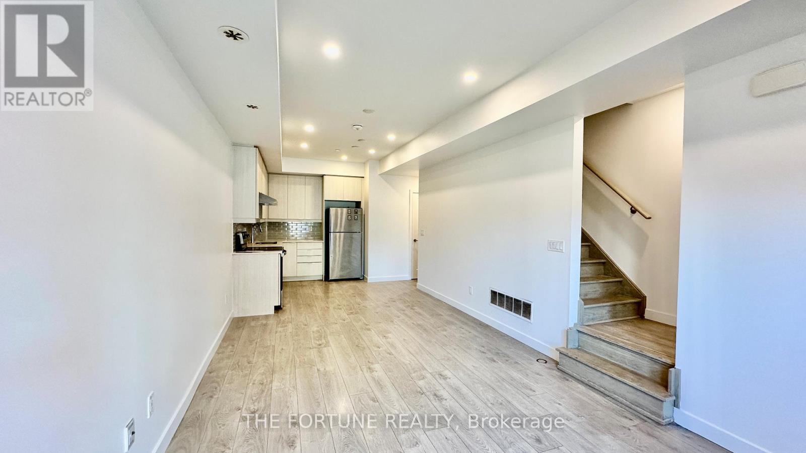 A spacious, well-lit living area with a staircase leading to another level.