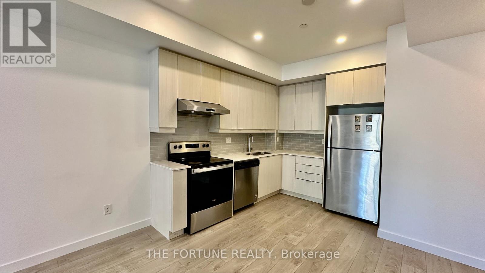A kitchen with a stainless steel refrigerator and a stove top oven.