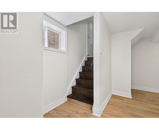 A staircase in a house with a white wall and wooden steps.