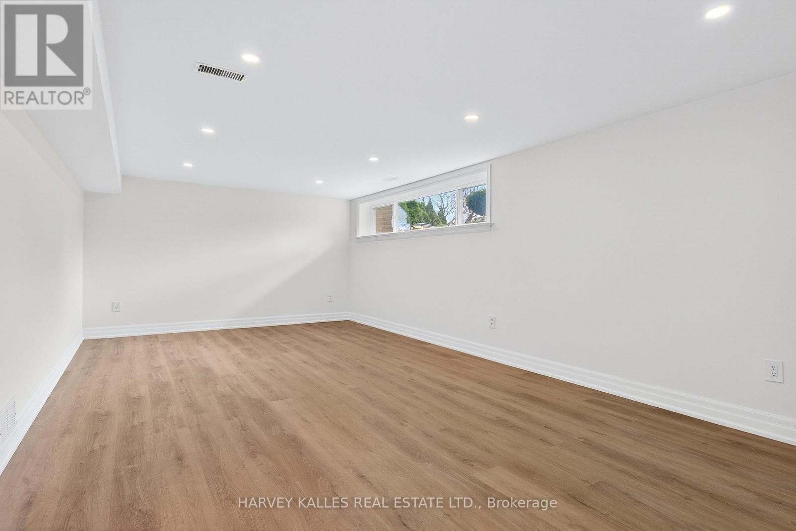 A spacious room with wooden flooring and white walls.