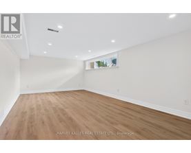 A spacious room with wooden flooring and white walls.