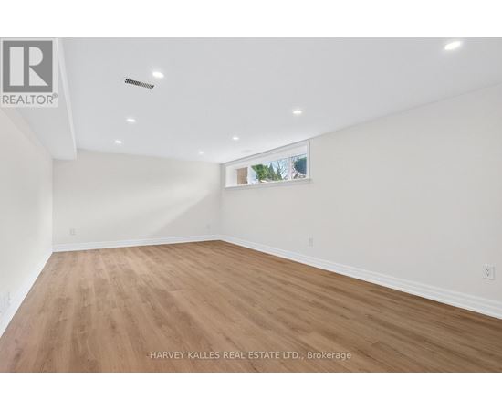 A spacious room with wooden flooring and white walls.