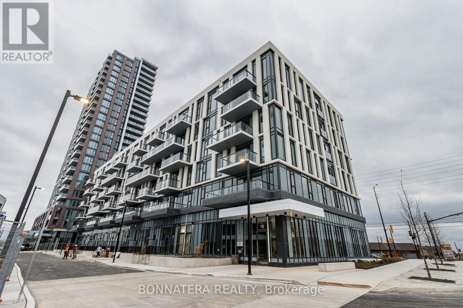 A modern building with glass windows and balconies is under construction with a sign that reads "Bonnatera Realty, Brokerage".