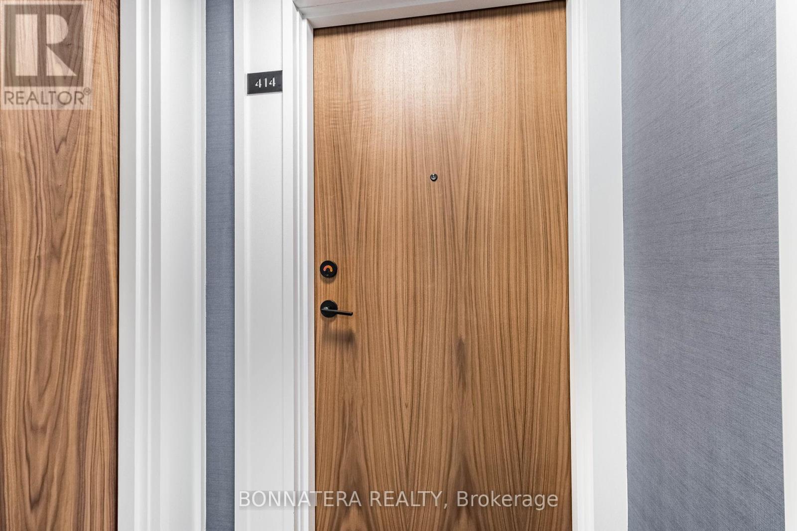 A wooden door with a black handle and a number 414 on it.