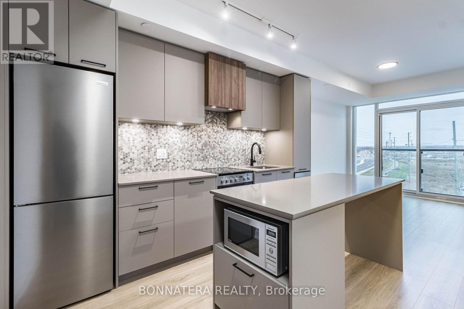 A modern kitchen with a stainless steel refrigerator and microwave.
