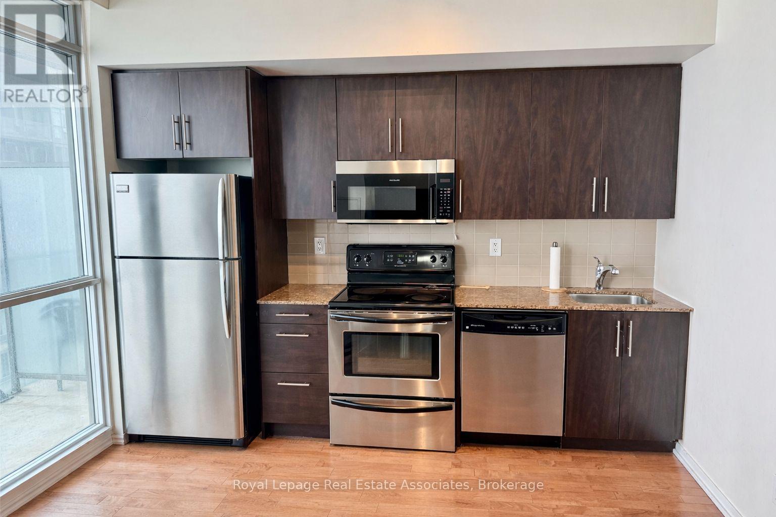 A kitchen with a stainless steel refrigerator, oven, and microwave.