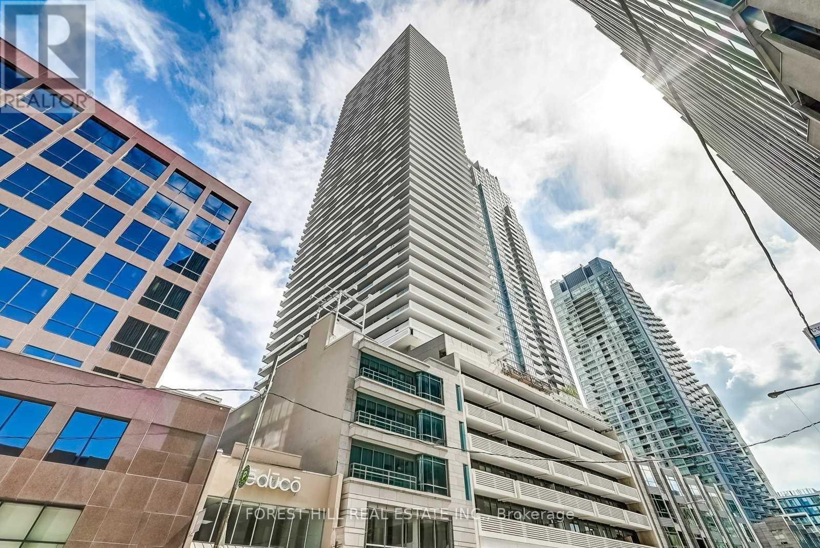 A tall building with a glass facade stands in front of a sky with clouds.