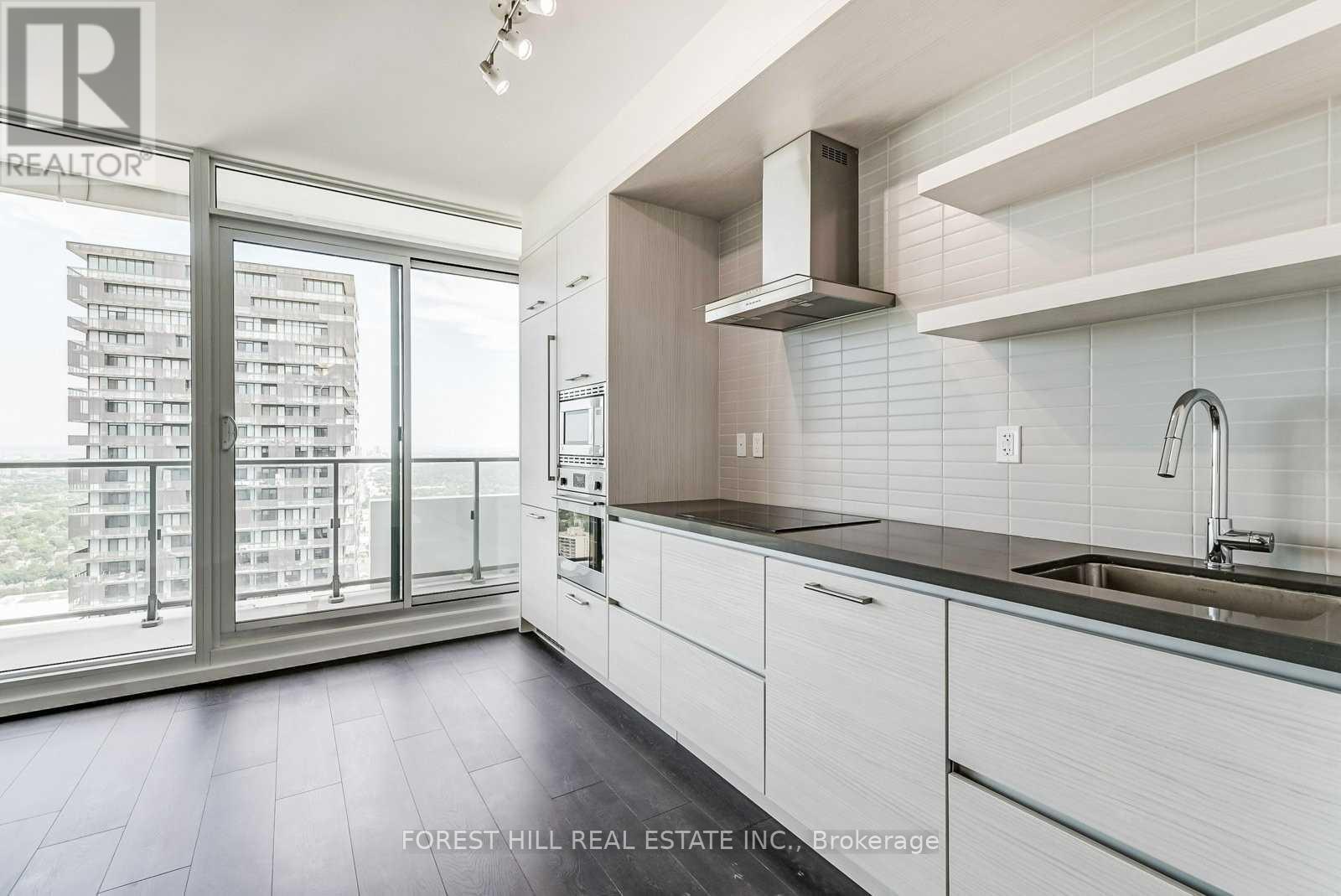 A modern kitchen with white cabinets and a stainless steel sink.
