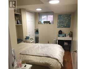 A bedroom with a bed, desk, and window.