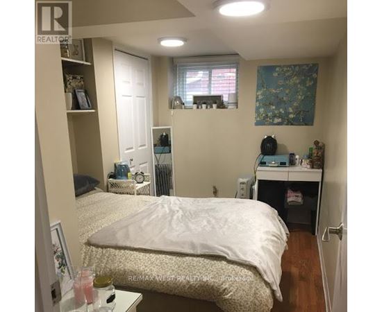 A bedroom with a bed, desk, and window.
