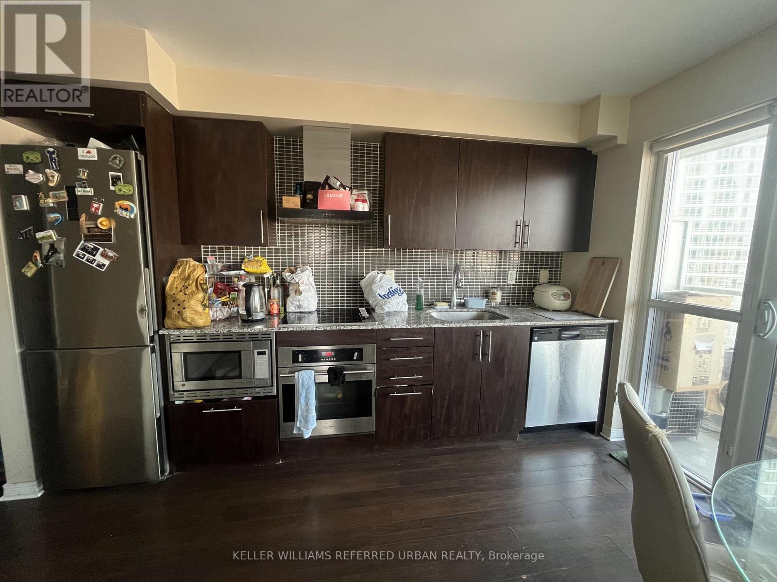 A kitchen with dark wood cabinets and a refrigerator covered in magnets.