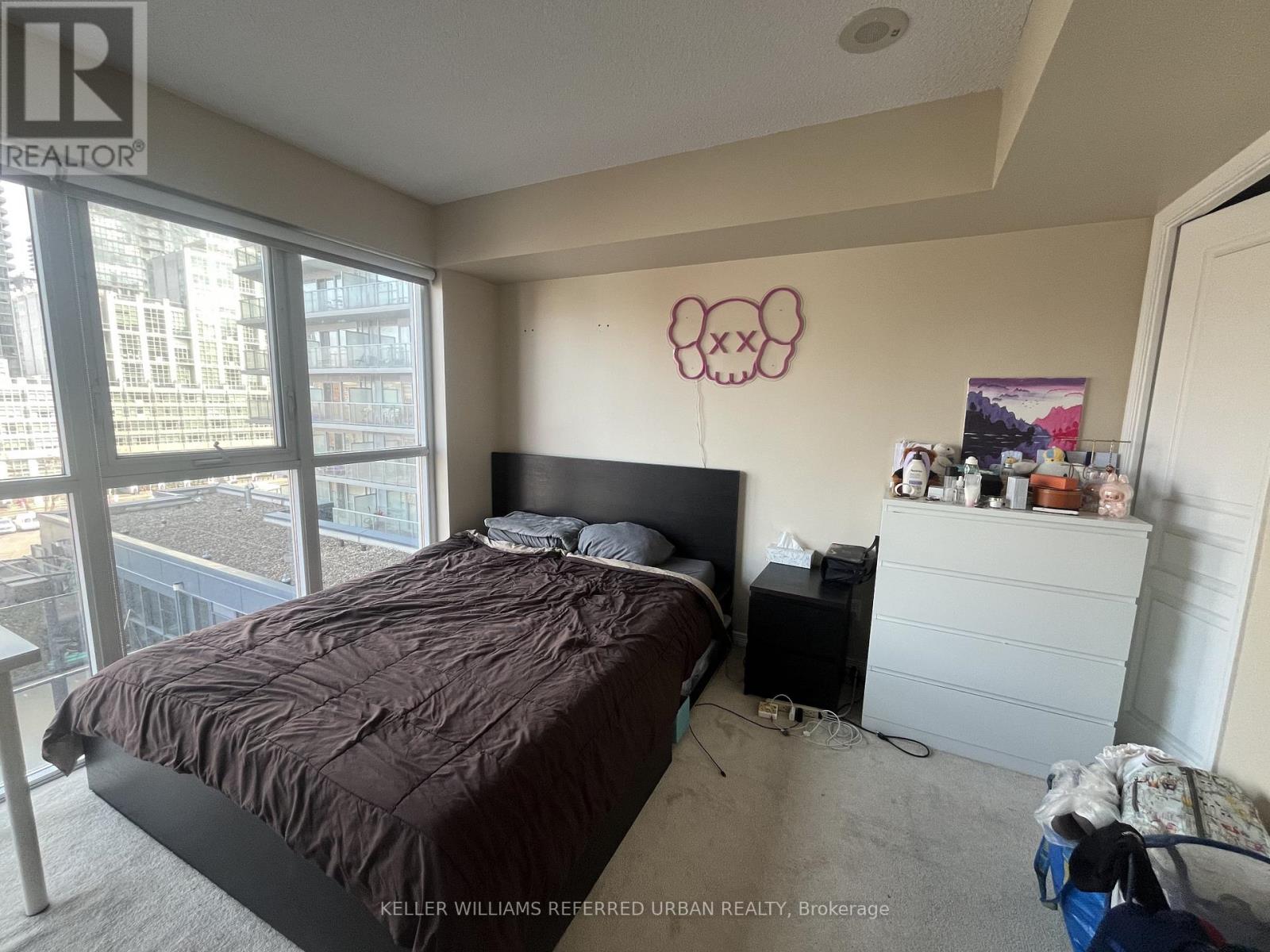 A bedroom with a large bed and a window overlooking a cityscape.