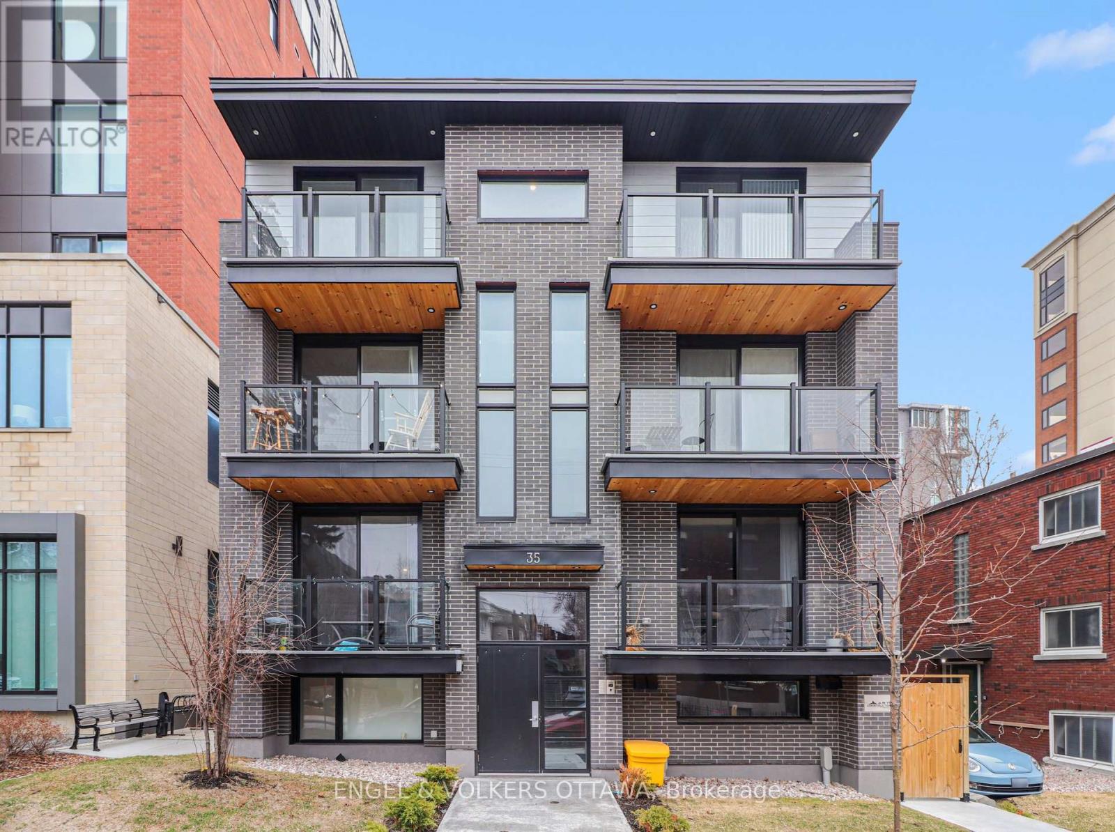 A modern multi-story building with balconies and a black door.