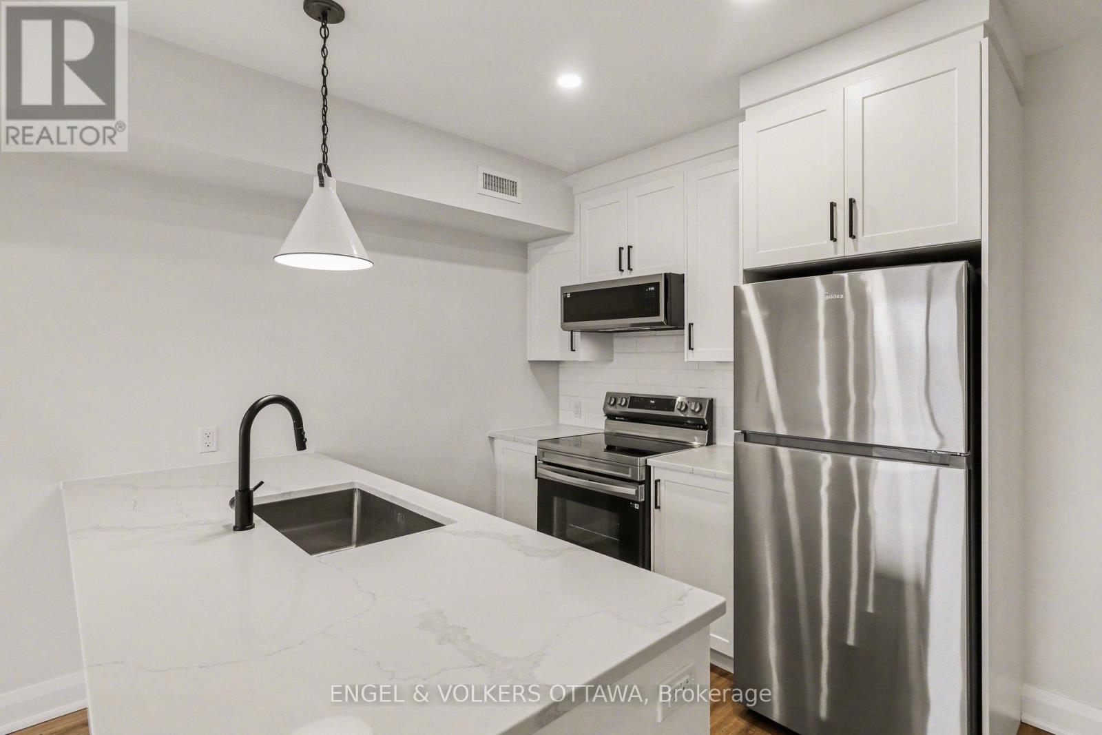 A modern kitchen with a stainless steel refrigerator and a marble countertop.