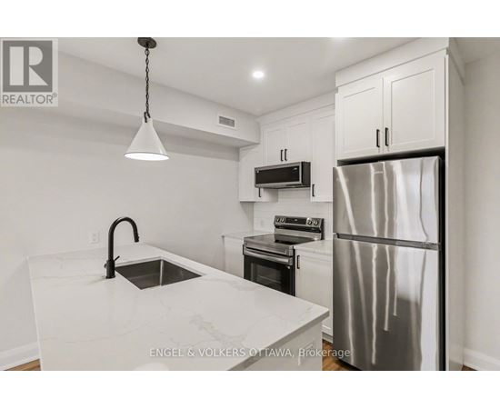 A modern kitchen with a stainless steel refrigerator and a marble countertop.