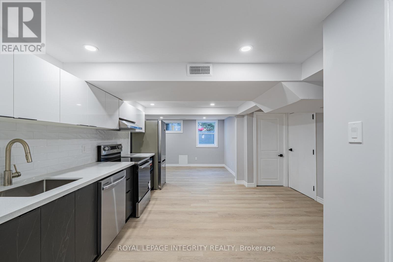A modern kitchen with white cabinets and a wooden floor.