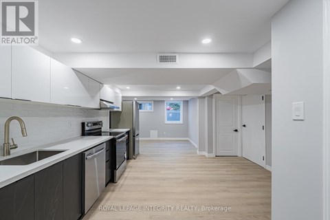 A modern kitchen with white cabinets and a wooden floor.