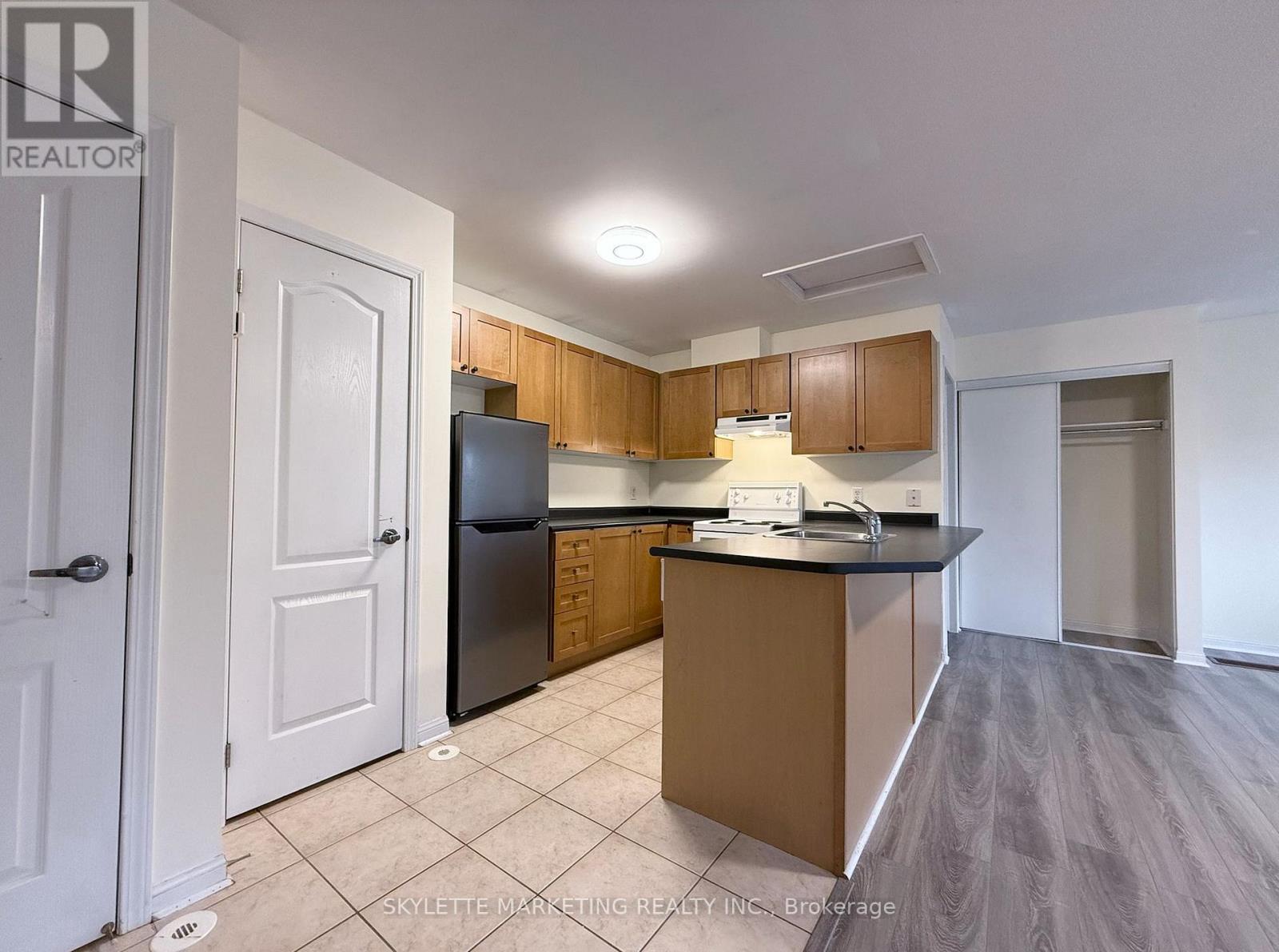 A kitchen with a black refrigerator and wooden cabinets.